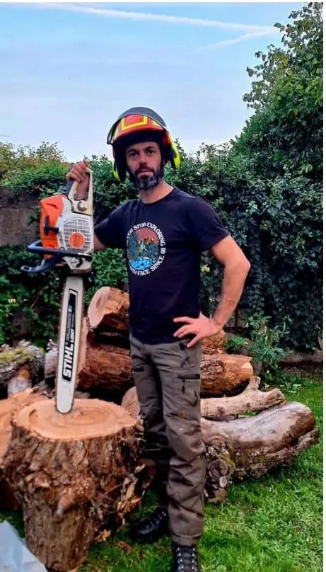 Fabien Roser, arboriste grimpeur de Tree'Top, tronçonneuse à la main devant des troncs débités.